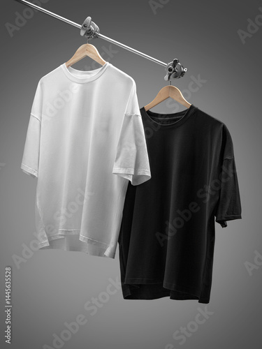 Two t-shirts, one black and one white, are neatly hanging on a metallic hanger.