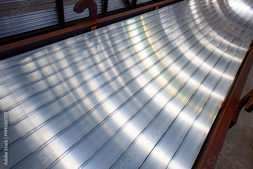 The aluminum products piled up in the warehouse of the aluminum factory, shining brightly under the light, form beautiful patterns
