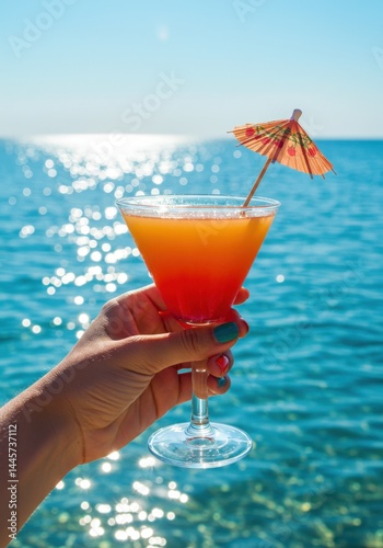 Vibrant tropical cocktail at oceanfront with decorative umbrella held by female hand