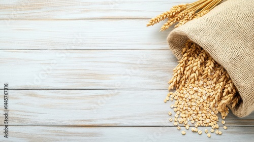 A burlap grain sack placed on a wooden table with grains like oats and barley spilling gently around it.