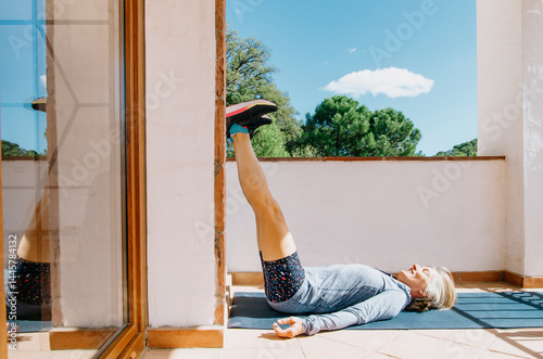 Restorative yoga for runners: woman doing legs up the wall pose on sunny terrace