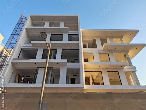 Under construction residential building structure
Highrise Skyscraper Exterior Modern Design Top Level View with blue sky background
Multi Storey Residential Building Site erected Scaffolding Around
