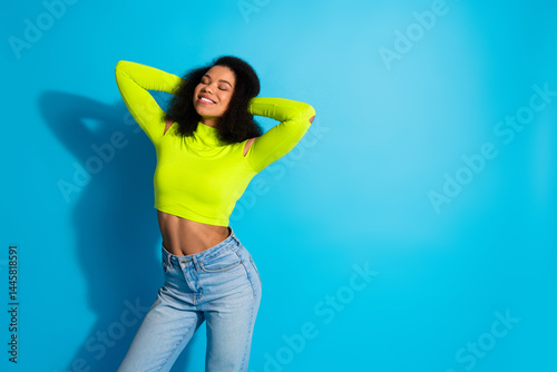 Smiling young woman posing confidently in neon green top against blue background exuding style, positivity, and a fashionable vibe