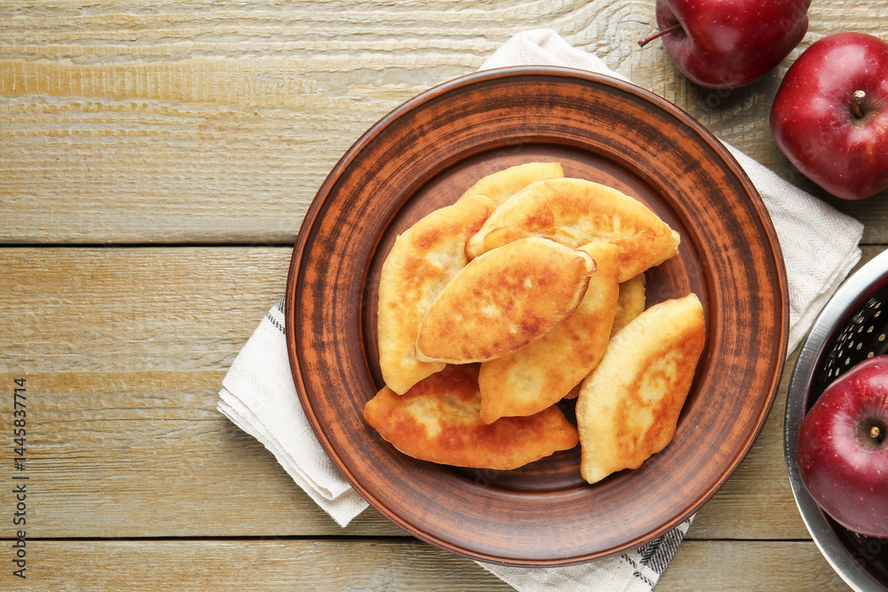 Delicious fried pyrizhky (stuffed pies) with apples on wooden table, flat lay. Space for text Delicious fried pyrizhky (stuffed pies) with apples on wooden table, flat lay. Space for text