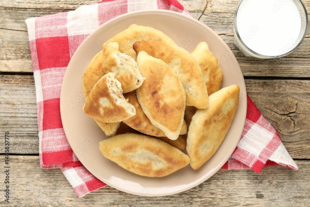 Delicious fried pyrizhky (stuffed pies) and milk on wooden table, top view Delicious fried pyrizhky (stuffed pies) and milk on wooden table, top view