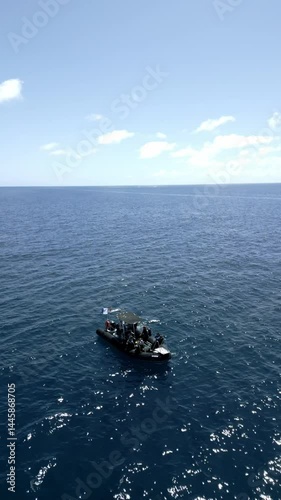 Scuba divers entering water with backward roll from inflatable boat
