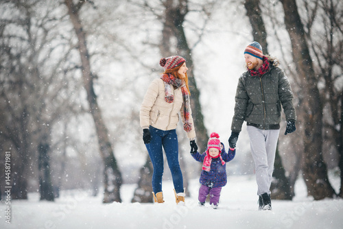 Young family with baby girl outdoors playing in the snow