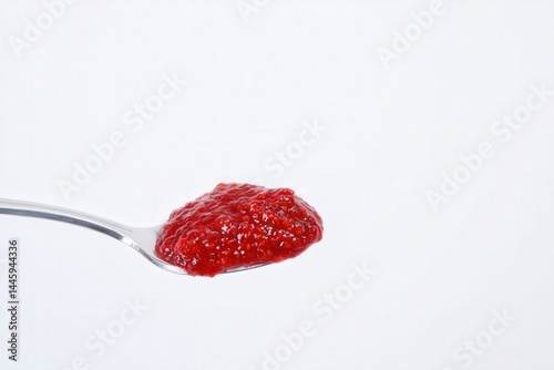Spoonful of fresh raspberry jam against white background
