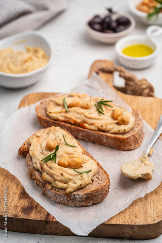 Obraz na płótnie Delicious sandwiches with hummus and ingredients on white table, flat lay. High quality photo w salonie