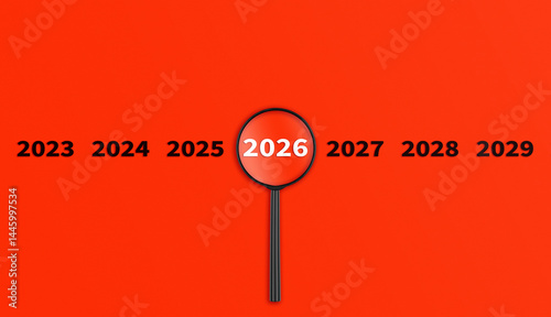 Obraz na płótnie Lens, magnifying glass focusing on the year 2026 on a red background. Financial or stock market strategies and past and future events. w salonie