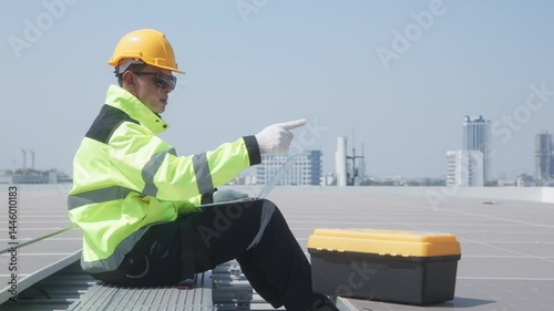 Engineer inspecting solar panels using laptop on rooftop