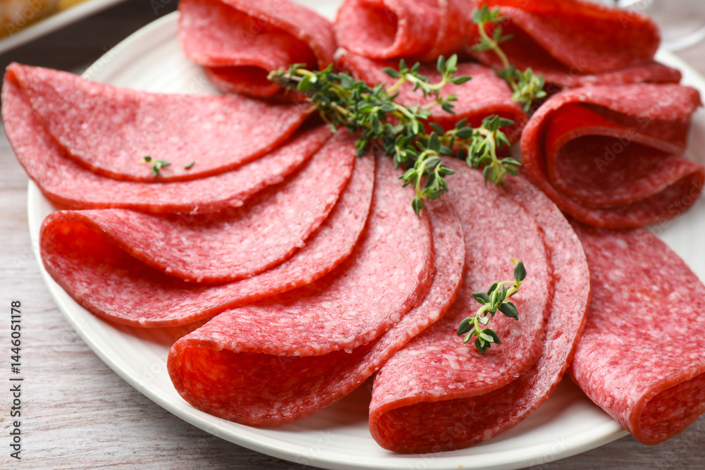 Slices of delicious sausage with thyme served on light wooden table, closeup Slices of delicious sausage with thyme served on light wooden table, closeup