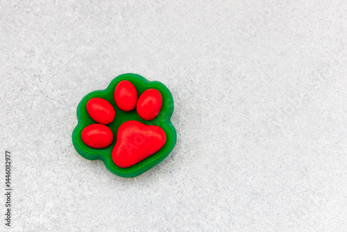Bright red paw print shaped toy sits on a light gray surface