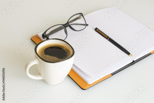 Office supplies. A notepad for notes, a pen, and a cup of coffee on the desk.