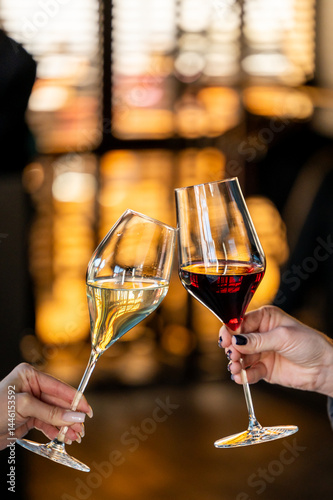 Wallpaper Mural Two hands clink elegantly designed glasses of white and red wine against a softly lit background, capturing a celebratory moment in a stylish setting. Torontodigital.ca