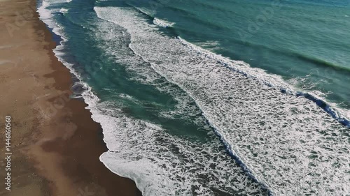 Powerful waves rolling, crashing against sandy coastline, highlighting dynamic marine energy and natural rhythmic movement