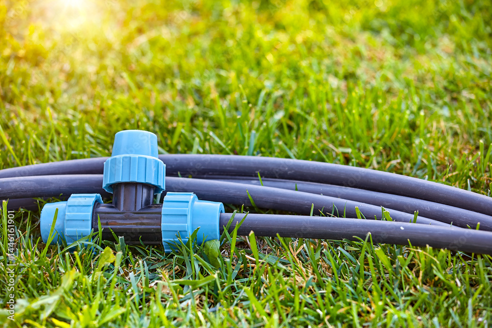 Fittings pipes and connectors for the garden and lawn irrigation system installation. Green grass, shallow depth of field. Place for text.