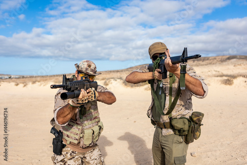 Soldiers in Tactical Gear Aim Rifles in Desert Terrain
