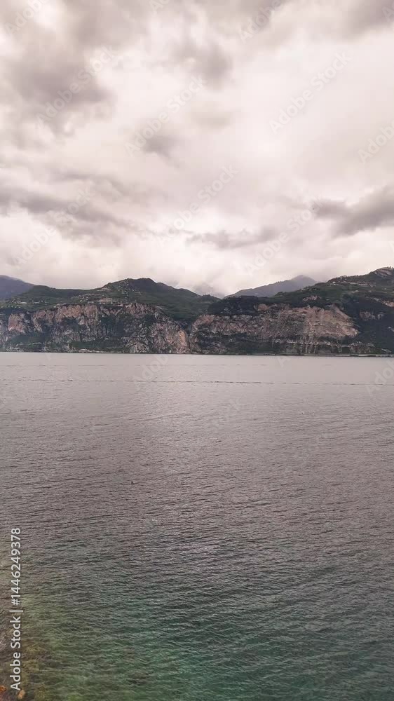 beautiful Lake Garda, Italy against the green mountains, flying over blue water on drone. in background a brunette girl in black. blue sky with white clouds, boats in the water