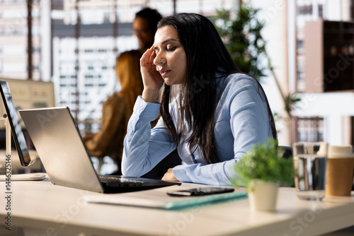 Corporate indian woman experiences business pressure at the office, overwhelmed by administrative tasks and deadlines. Manager with frustration dealing with fatigue and low energy.