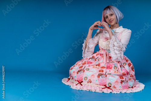 Photos Kawaii girl making heart shape with hands in studio with blue background