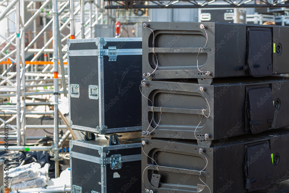 Stacks of sound equipment and lighting gear are arranged at an outdoor venue, ready for a concert. Stacks of sound equipment and lighting gear are arranged at an outdoor venue, ready for a concert.