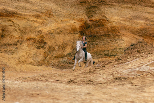 Obraz na płótnie A young woman and her white icelandic horse gelding interacting in a sand pit; horsemanship concept w salonie