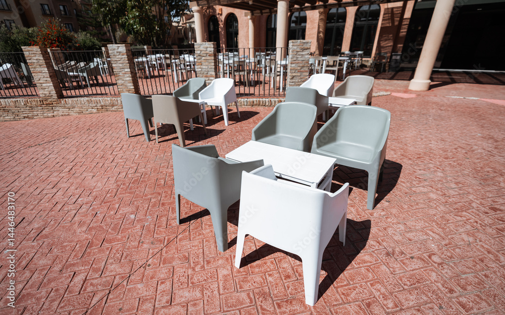 custom made wallpaper toronto digitalModern outdoor patio with empty plastic chairs and white tables on red patterned tiles, sunlit terrace area of a restaurant or hotel, no people, sunny clear day