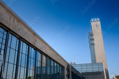 Main façade of Riga Centrala stacija with long glazed concourse and iconic clock-tower spelling, a key transport hub for Baltic rail passengers. It's the main train station of Riga, Latvia. photo