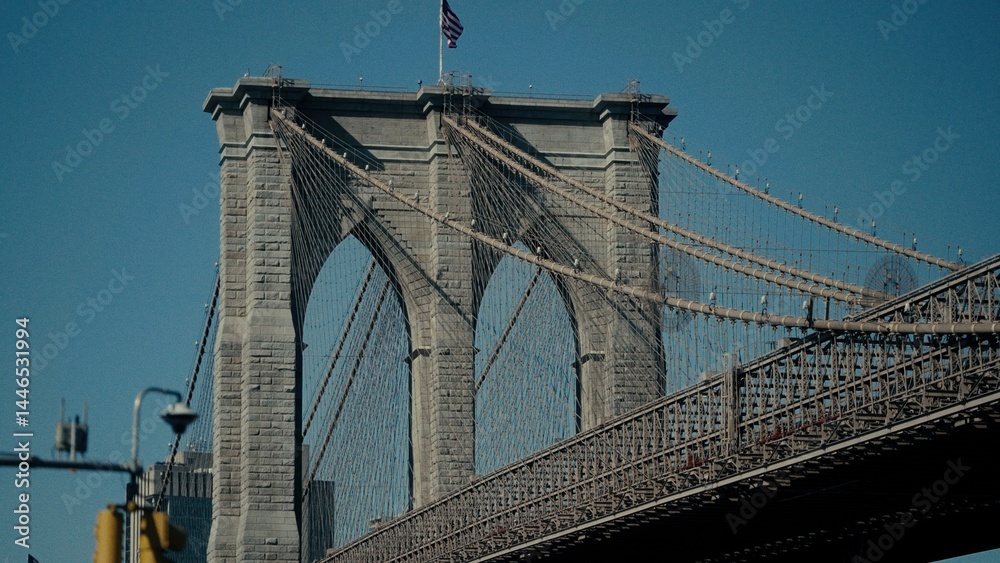 Fototapeta premium Low angle view of Brooklyn Bridge with waving american flag in New York City, USA