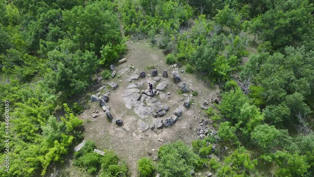Man standing at the center of an ancient stone circle surrounded by lush green forest, highlighting historical heritage and spiritual outdoor landmarks.