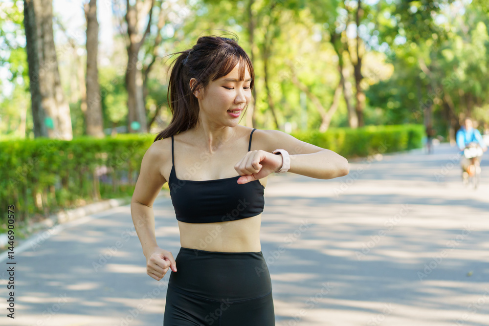 Fototapeta premium Asian woman using smartwatch or tracker to track her workout progress.