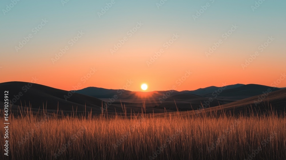 Obraz premium The sun is setting behind the distant rolling mountain landscape