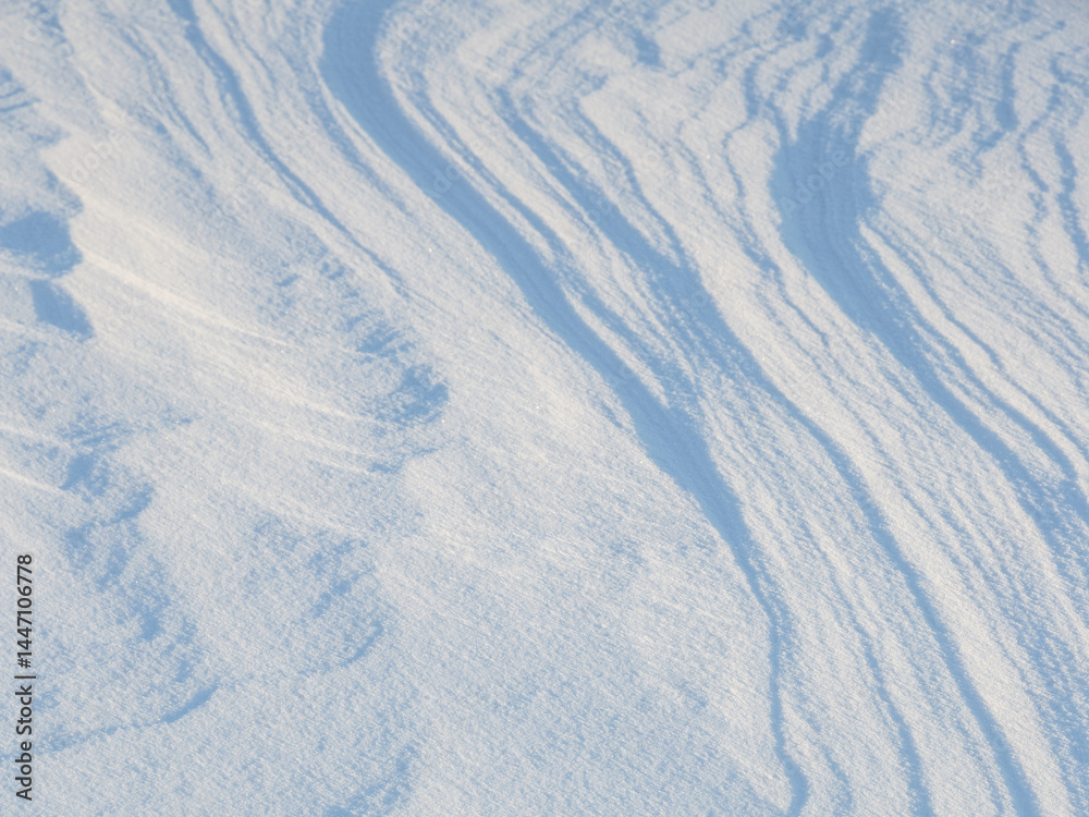 Beautiful winter background with snowy ground. Natural snow texture. Wind sculpted patterns on snow surface.