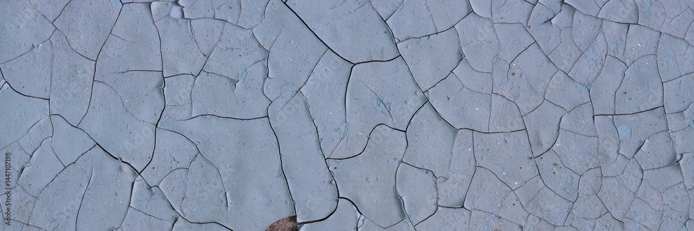 Peeling paint on the wall. Panorama of a concrete wall with old cracked flaking paint. Weathered rough painted surface with patterns of cracks and peeling. Panoramic texture for background and design.