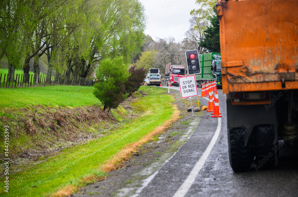 STOP ON RED SIGNAL road sign and traffic cones on the road. Heavy trucks stopped at the red light. North Island. New Zealand.
