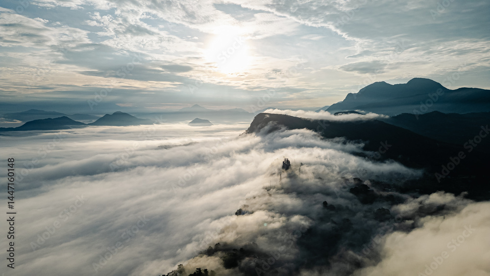 Fototapeta premium Majestic mountain peaks emerging through a sea of clouds at dawn