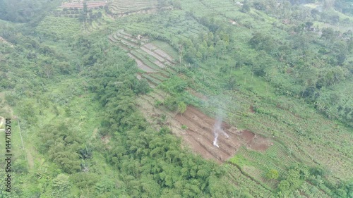 Aerial View of Lush Green Hillside Farmland with Smoke