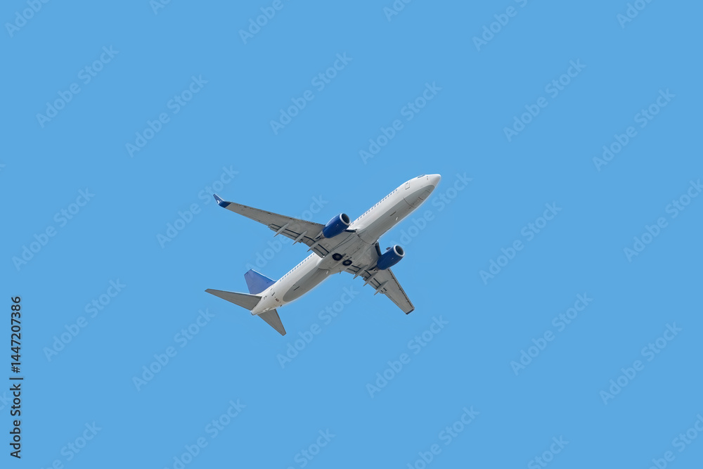 Bottom view of passenger plane taking off in blue sky Bottom view of passenger plane taking off in blue sky