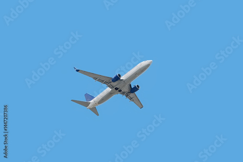 Bottom view of passenger plane taking off in blue sky