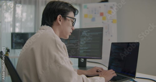 Wallpaper Mural Young asian software developer analyzing project documents and reviewing coding tasks in a modern office environment, focusing on technology and professional work. Torontodigital.ca