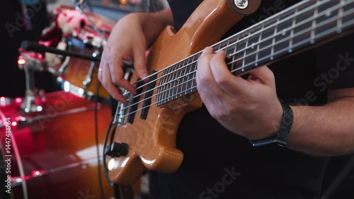 Close-up, unrecognizable musician bassist plays bass guitar at concert, party, event, wedding. Hands of bassist play musical instrument skillfully actively moving to beat of music and pressing notes