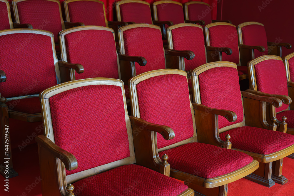 Fototapeta premium Empty rows of retro, old red theater or cinema seats. Old style, vintage chairs with red upholstery in concert hall.