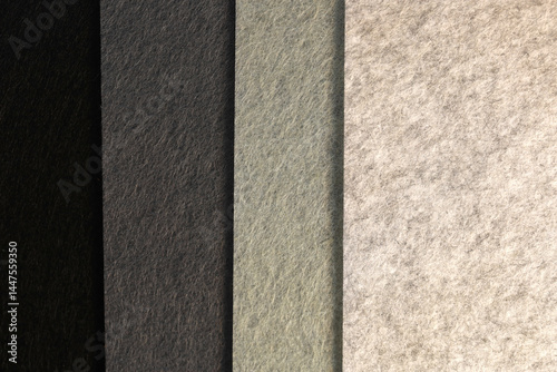 Different shades of dark felt folded vertically on top of each other. Black color and different shades of gray color palette of felt.