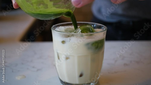 Iced Green matcha latte tea and pouring milk in glass