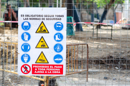 March 27 2022 - Spain. Warning and mandatory safety sign at a fenced construction site. The sign in Spanish lists required safety equipment and prohibits unauthorized entry.