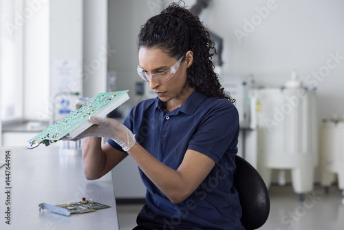 Woman Inspecting Electronic Circuit Board