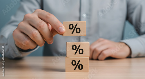 Person Stacking Wooden Blocks with Percentage Signs Representing Interest Rates and Financial Growth on Wooden Desk