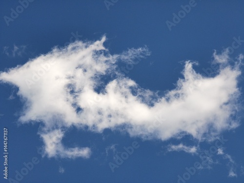 Distinctively shaped white cloud with uneven, jagged edges floats against a vivid blue sky, creating an airy and imaginative sky background