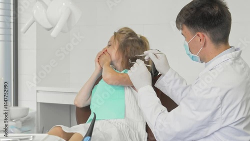 Young girl covering her mouth, refusing to show teeth to a dentist